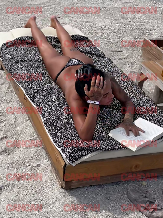 Livia Eftimie, la plajă, fără sutien, citind o carte.