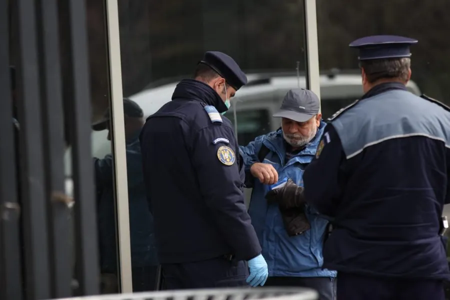 Doi poliţişti îl verifică pe un bărbat în etate care a ieşit astăzi pe o stradă din Bucureşti © CANCAN.RO