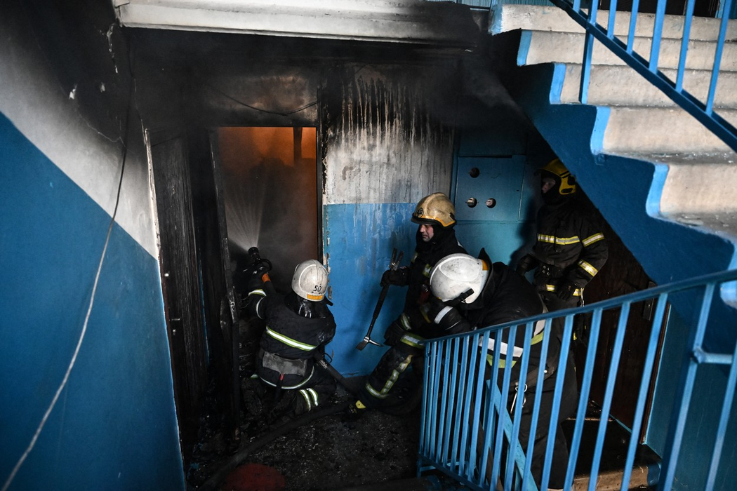 Pompierii lsting un incendiu într-o clădire, după bombardamentele asupra orașului Chuguiv, din estul Ucrainei, din 24 februarie 2022. (Sursa foto: profimedia.ro)