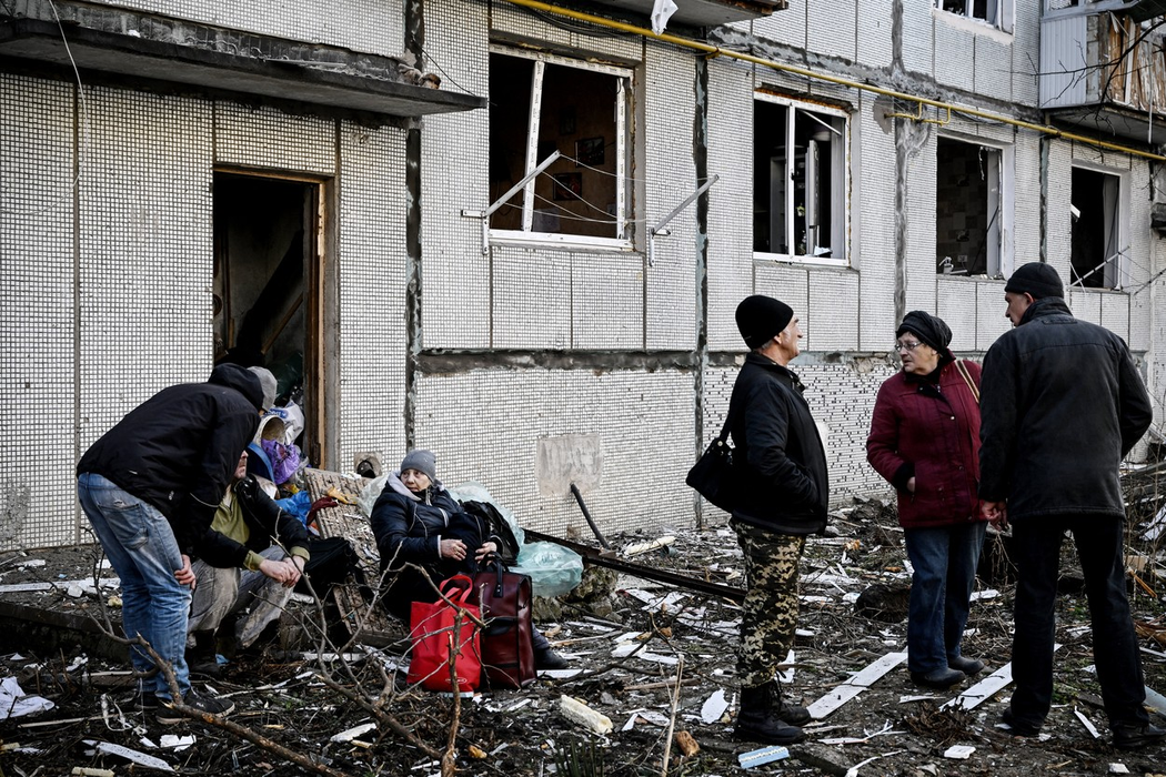 Oamenii stau în faţa unei clădiri distruse, după bombardamentele din Chuguiv, oraş din estul Ucrainei. Sursa foto: Profimedia Images