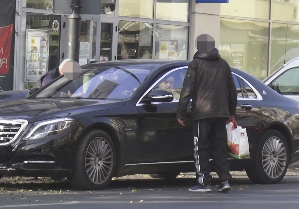 Cerșetorul așteaptă lângă mașină o sumă de bani