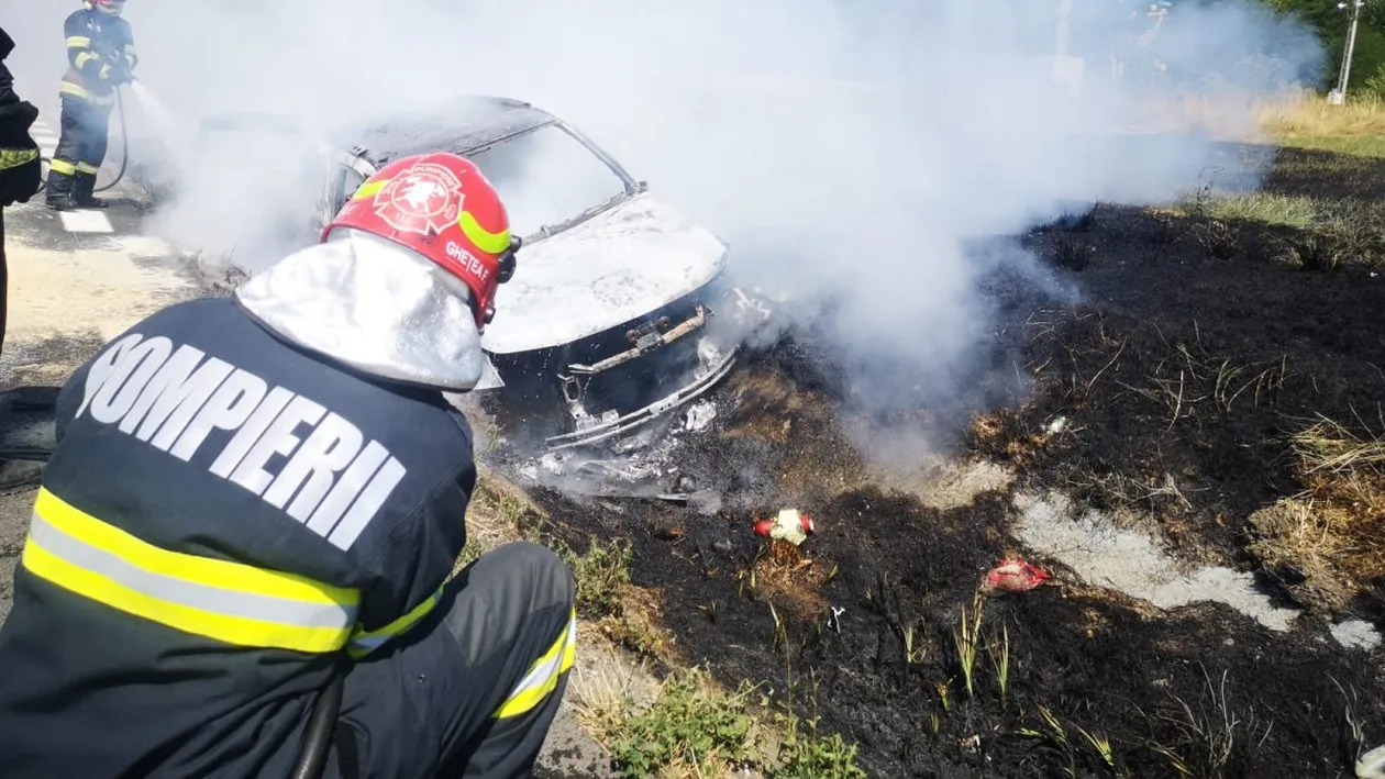 Haos după un accident rutier! O mașină a luat foc, vegetația s-a aprins și amenință o stație peco