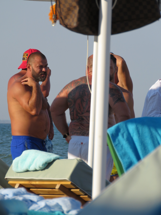 Nuţu (în şort alb) discută pe plajă cu prietenii săi