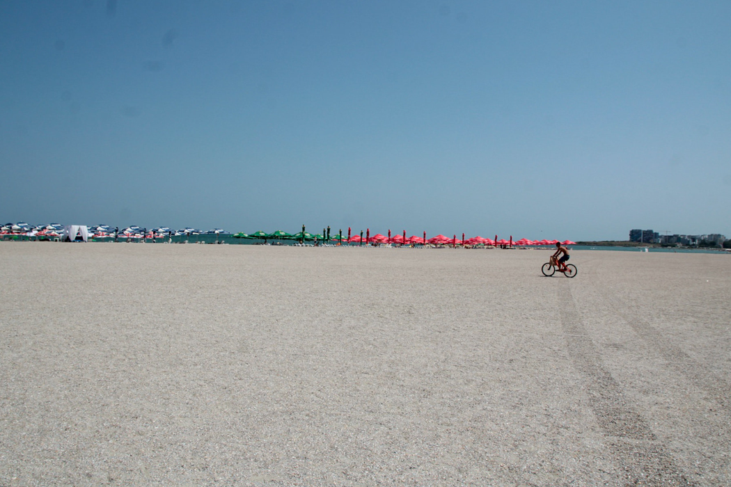 Un tânăr livrează pe bicicletă o comandă la un turist, pe plaja din Mamaia. Sursă foto: Facebook ”Bucharest”