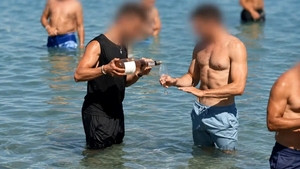 Scenă controversată pe o plajă din Grecia. Ospătarul merge prin apă cu vinul pentru turiști