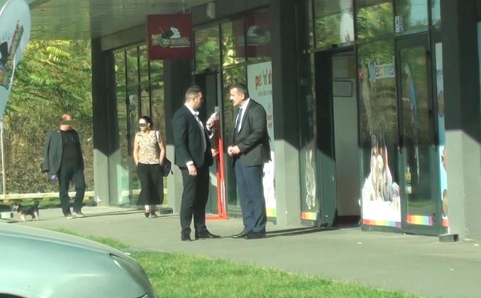 Cei doi discută despre ceva, în timp ce o doamnă şi un domn cu un căţel se apropie