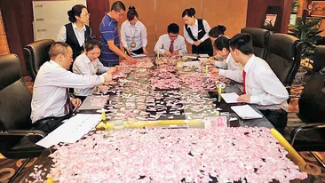 Munca de Sisif pentru angajatii unei banci din China! S-au chinuit Sase ore sa lipeasca 8.000 $ rupti