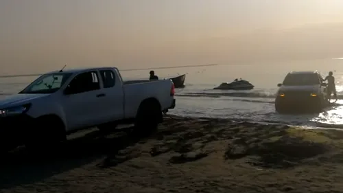 O mașină care a ajuns în mare, filmată pe o plajă din zona Mamaia Nord