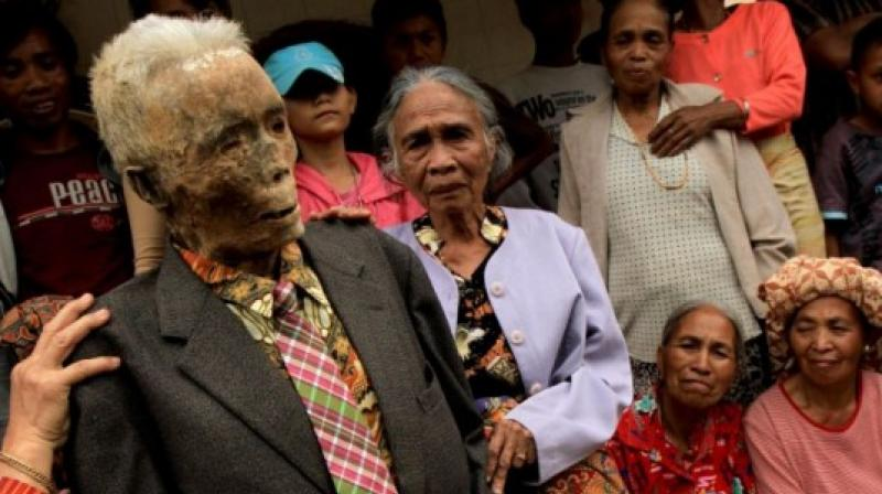 Ritual bizar pe o insula din Indonezia! O dată la trei ani, familiile își dezgroapă morții și apoi stau cu ei la o țigară