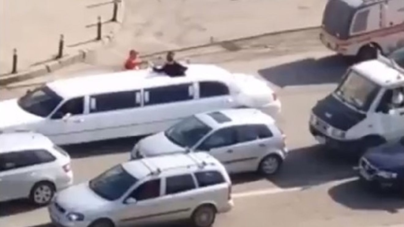 Un muncitor de la asfaltări bea şampanie lângă o limuzină, pe un bulevard din Craiova
