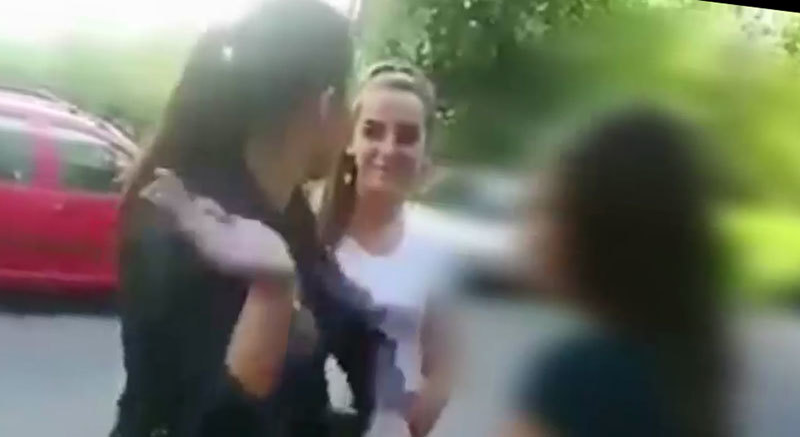 Una dintre agresoare se pregăteşte să trimită o palmă colegei sale