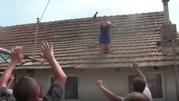 Scene greu de imaginat la o nuntă! S-a urcat pe casă şi a început să arunce cu ţigle în nuntaşii care o plăteau