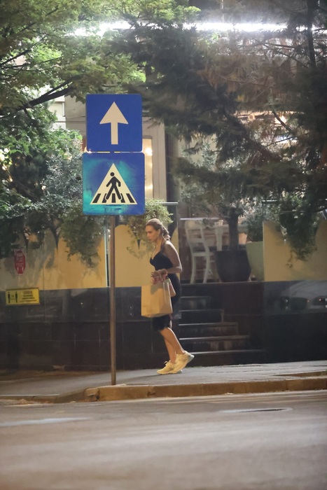 Iulia Vântur se retrage de la terasă, cu plasele în mâini, după ce, în prealabil, făcuse și un scurt shopping (Foto: CANCAN.RO)