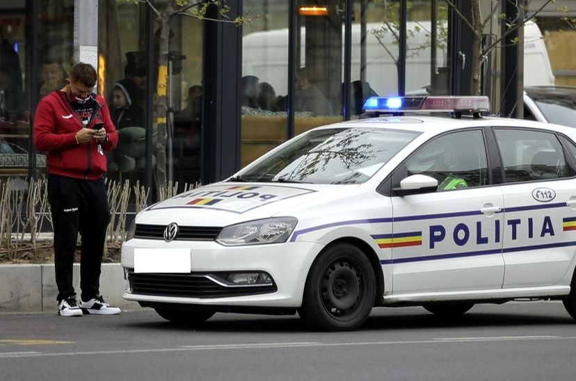 Cătălin Moroșanu își verifică telefonul lângă mașina de Poliție