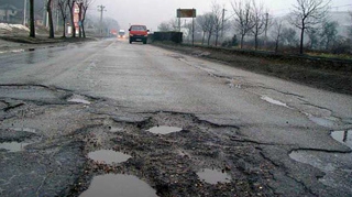 Un pensionar din Santuhalm, de pe DN 7, a semnalizat gropile din fata casei sale cu trunchiuri de brazi!