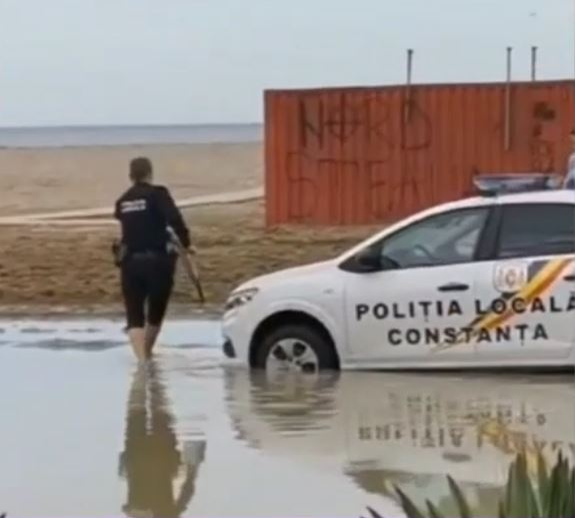 Polițistul care și-a suflecat pantalonii, după ce mașina de poliție a rămas împotmolită