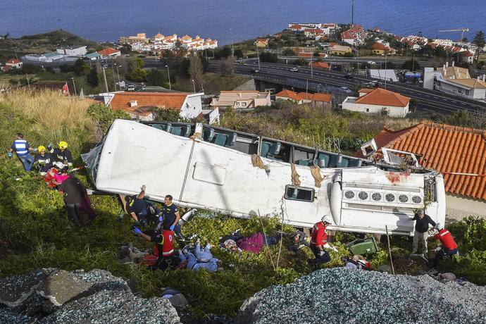 Rescue officials attend the scene after a tour bus crashed in Canico on Portugal's Madeira Island, Wednesday, April 17, 2019. The tour bus carrying German tourists crashed on Portugal's Madeira Island on Wednesday, killing more than a few dozen people and injuring a few dozen others, local authorities said. (Rui Silva/Aspress/Global Imagens via AP)
