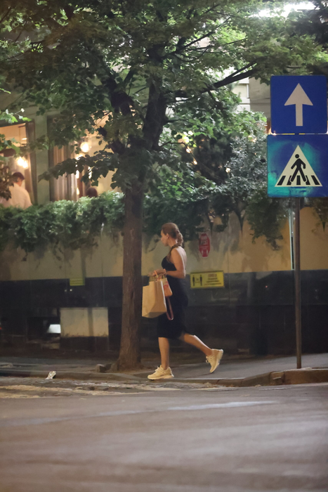 Iulia Vântur se retrage de la terasă, cu plasele în mâini, după ce, în prealabil, făcuse și un scurt shopping (Foto: CANCAN.RO)