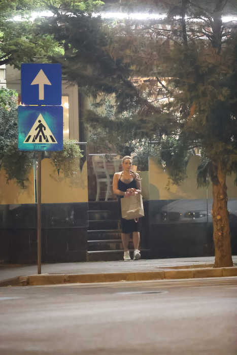 Iulia Vântur se retrage de la terasă, cu plasele în mâini, după ce, în prealabil, făcuse și un scurt shopping (Foto: CANCAN.RO)