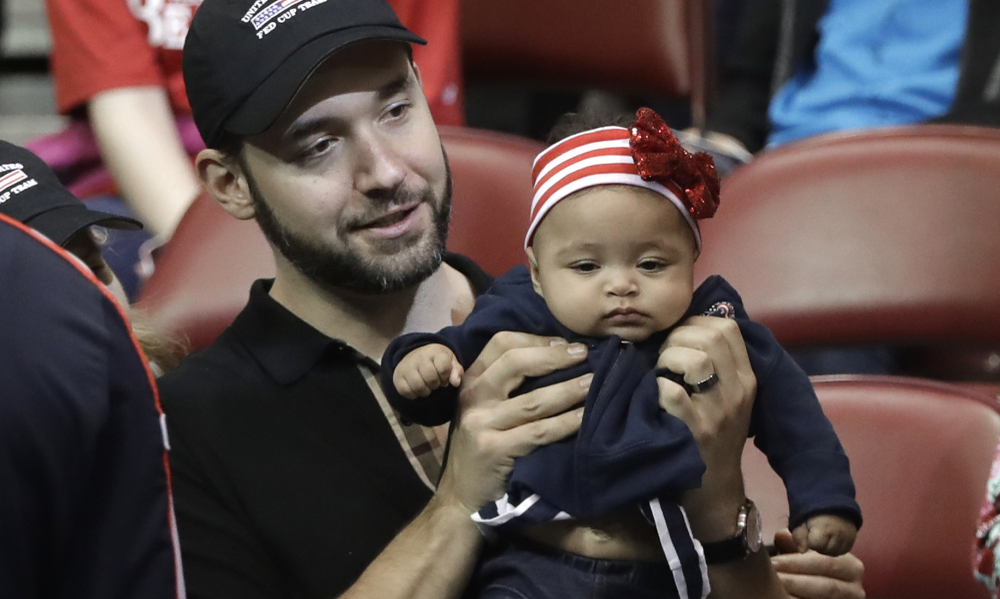 Alexis Ohanian, husband of USA's Serena Williams, holds their baby, Alexis Olympia Ohanian Jr., before the doubles match in the first round of Fed Cup tennis competition in Asheville, N.C., Sunday, Feb. 11, 2018. (AP Photo/Chuck Burton)