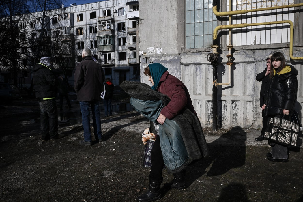 Oamenii părăsesc clădirea distrusă, după bombardamentele asupra orașului Chuguiv, din estul Ucrainei, pe 24 februarie 2022. (Sursa foto: profimedia.ro)