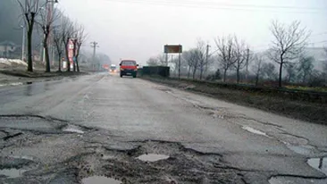 Un pensionar din Santuhalm, de pe DN 7, a semnalizat gropile din fata casei sale cu trunchiuri de brazi!