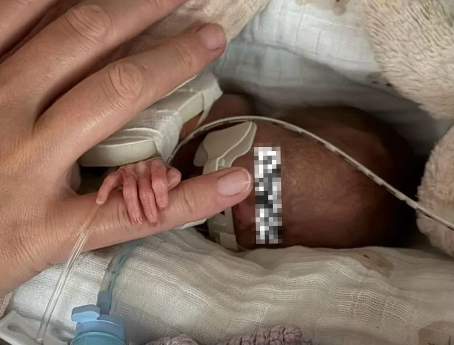 fetita nascuta prematur care tine degetul mic al mainii mamei sale