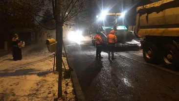 Nici vremea rea nu-i împiedică pe drumari! La Craiova se asfaltează pe ninsoare