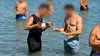 Scenă controversată pe o plajă din Grecia. Ospătarul merge prin apă cu vinul pentru turiști
