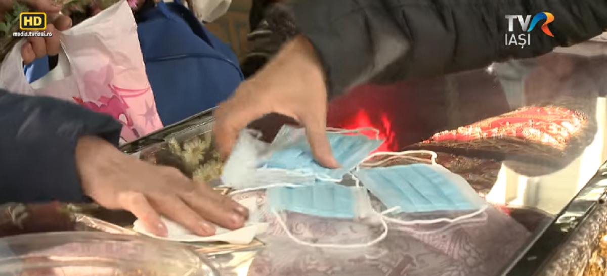 Caz șocant la Iași! Femeie filmată în timp ce șterge un mănunchi de măști de protecție de racla moaștelor Sfintei Paracheva:” Duc măștile acasă…”