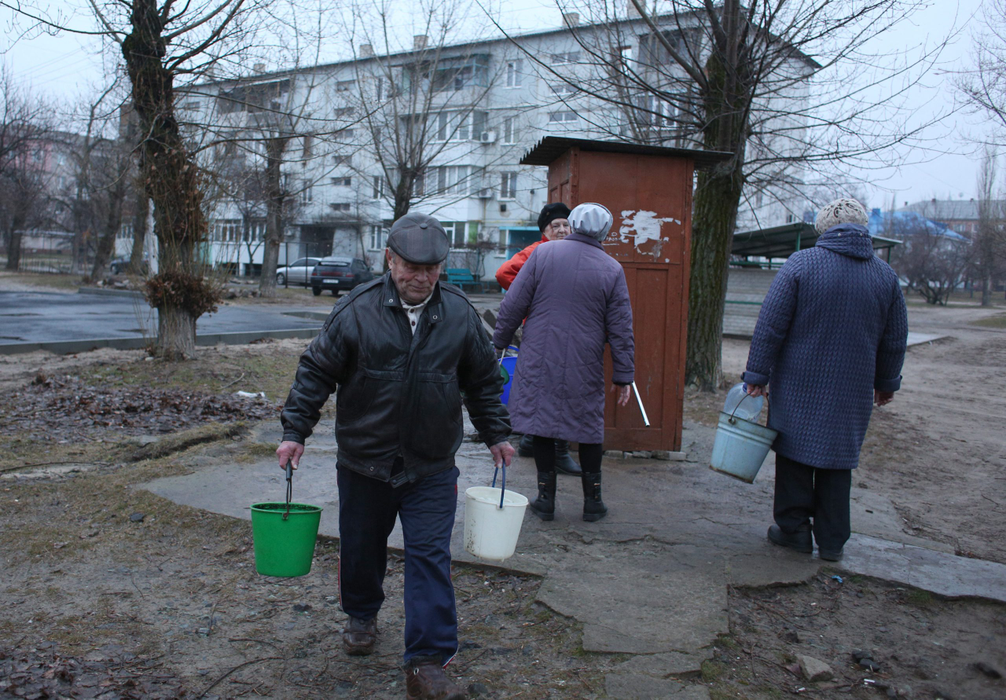 Oamenii aduc apă  dintr-o fântână din orașul Schastia, în apropiere de orașul Lugansk, din estul Ucrainei, pe 23 februarie 2022, după ce bombardamentele au distrus rețeaua de curect. (Sursa foto: profimedia.ro)