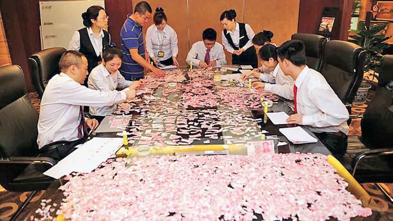 Munca de Sisif pentru angajatii unei banci din China! S-au chinuit Sase ore sa lipeasca 8.000 $ rupti