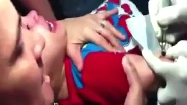 Momente teribile! O mamă îşi ţine copilaşul de trei ani, în timp ce acesta se zbate şi plânge, pentru a-i face un tatuaj!