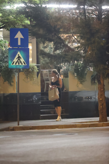 Iulia Vântur se retrage de la terasă, cu plasele în mâini, după ce, în prealabil, făcuse și un scurt shopping (Foto: CANCAN.RO)