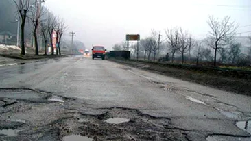 Un pensionar din Santuhalm, de pe DN 7, a semnalizat gropile din fata casei sale cu trunchiuri de brazi!