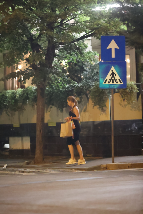 Iulia Vântur se retrage de la terasă, cu plasele în mâini, după ce, în prealabil, făcuse și un scurt shopping (Foto: CANCAN.RO)