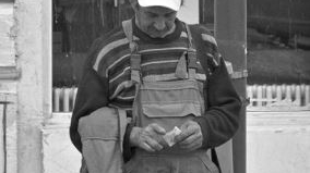Fotografie emoționantă. Ce scrie pe șapca acestui bărbat din Iași, care ține, trist, în mână, o bancnotă de 1 leu