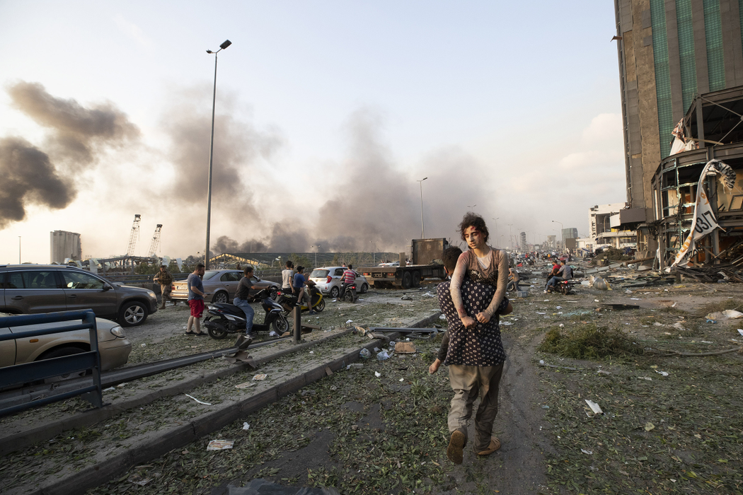 People evacuate wounded after of a massive explosion in Beirut, Lebanon, Tuesday, Aug. 4, 2020. Massive explosions rocked downtown Beirut on Tuesday, flattening much of the port, damaging buildings and blowing out windows and doors as a giant mushroom cloud rose above the capital. Witnesses saw many people injured by flying glass and debris. (AP Photo/Hassan Ammar)