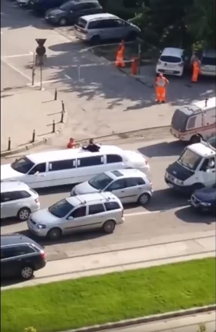 Un muncitor de la asfaltări bea şampanie lângă o limuzină, pe un bulevard din Craiova