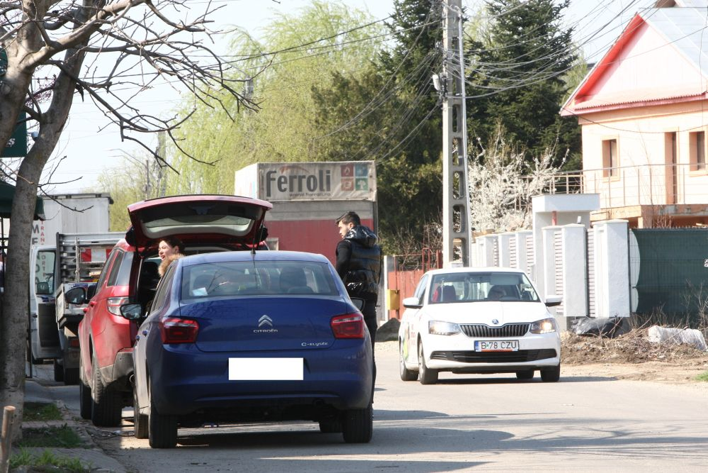 Oana Roman se îndreaptă spre poartă, în timp ce Marius Elisei se duce să-i deschidă ușa Isabelei