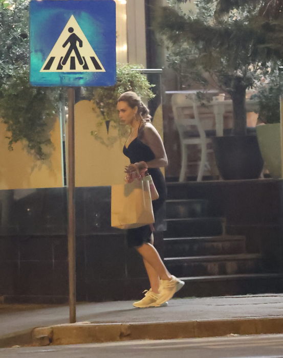 Iulia Vântur se retrage de la terasă, cu plasele în mâini, după ce, în prealabil, făcuse și un scurt shopping (Foto: CANCAN.RO)
