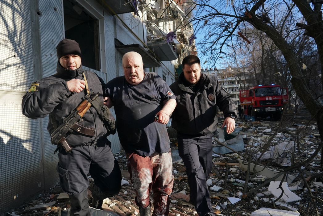 Forțele de securitate ucrainene însoțesc un bărbat rănit, după un atac aerian la Harkiv, 24 februarie, 2022. (Sursa foto: hepta.ro)